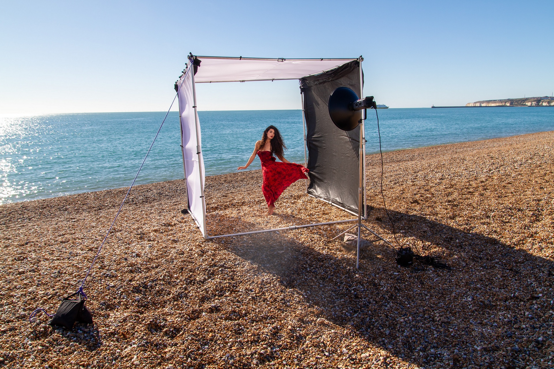 Model wearing a red dress on the beach - photo Taken by Brendan Bishop with his light tent